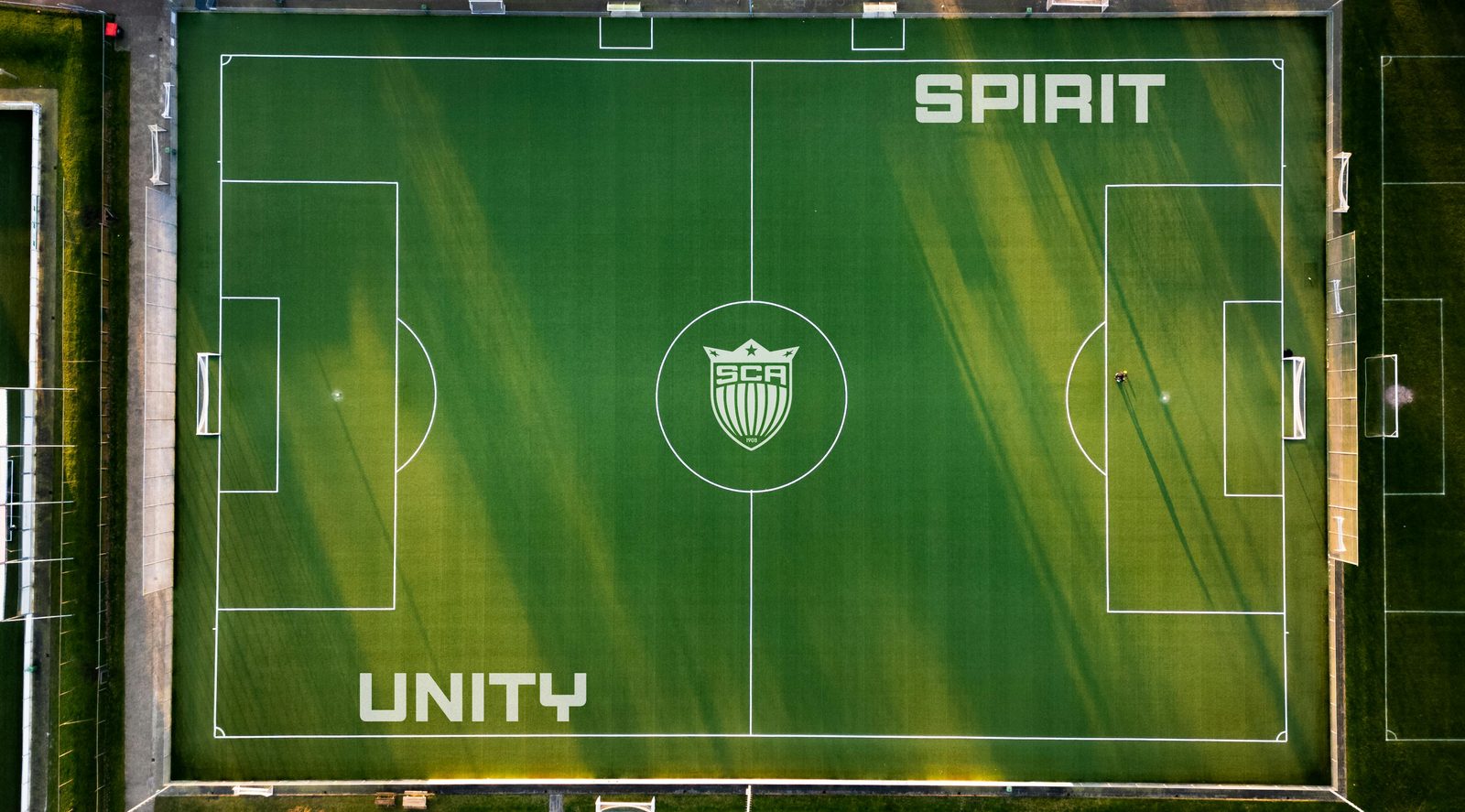 Pitch branding — SPIRIT and UNITY, crest at center